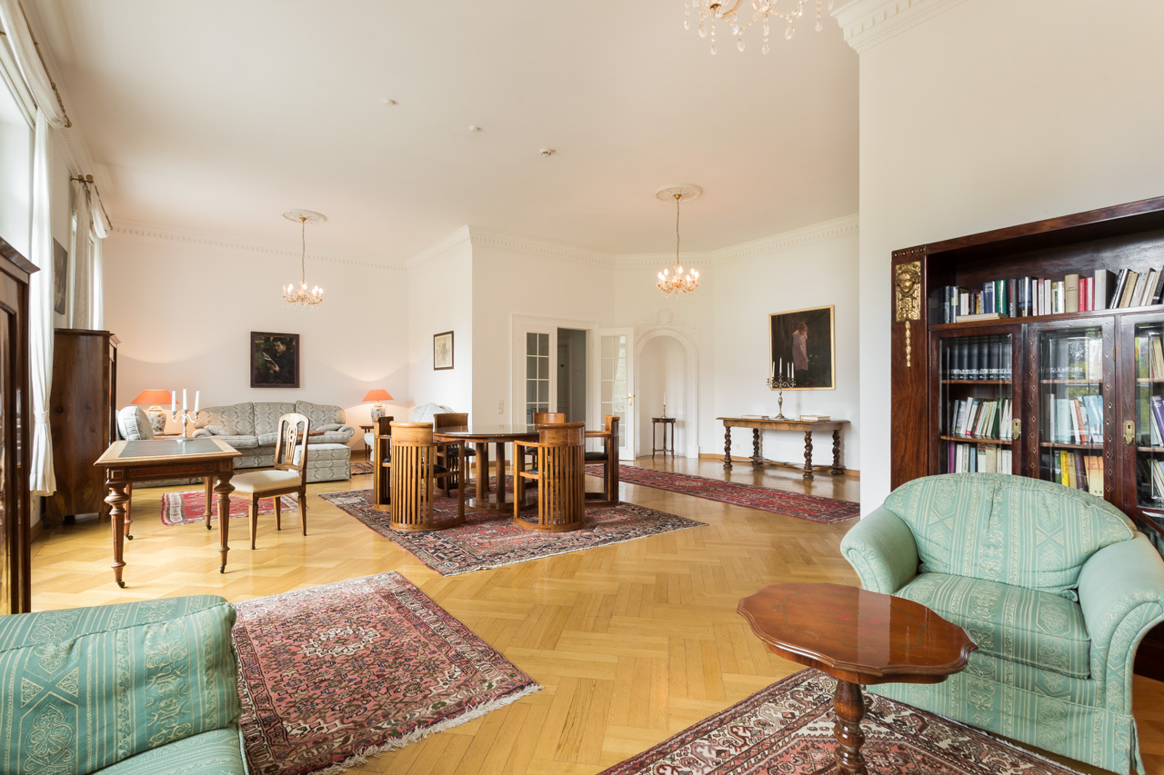 Salon mit Sitzgruppen Großzügiger Salon im Hotel Schloss Storkau mit Parkettboden, mehreren Sitzgruppen, Schreibtisch und Bücherschrank