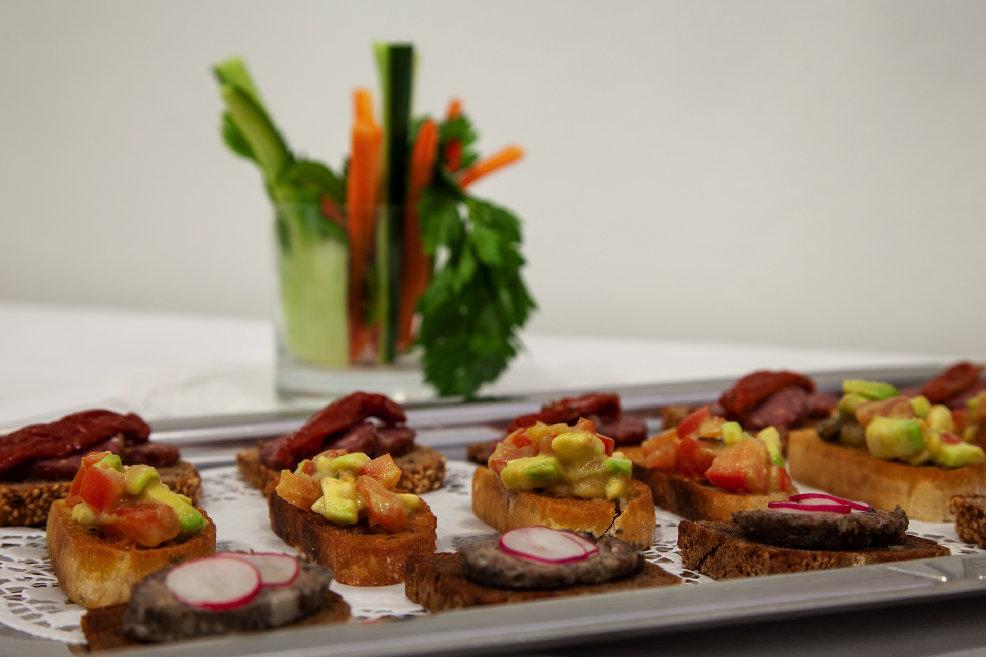 Silbertablett mit Canapés: Avocado-Tomate auf Baguette, Salami und Pastete auf Vollkornbrot mit Radieschen