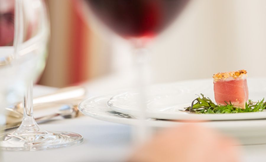 Thunfisch im Sesammantel Sesamummantelter Thunfisch auf Rucola im Hotel Schloss Storkau, im Vordergrund ein Glas Rotwein