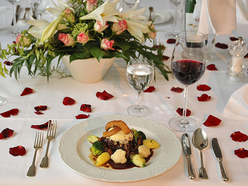 Festlich angerichteter Hauptgang im Hotel Schloss Storkau mit Fleisch, Kartoffeln, Brokkoli und Blumenkohl, dekoriert mit Rosenblättern