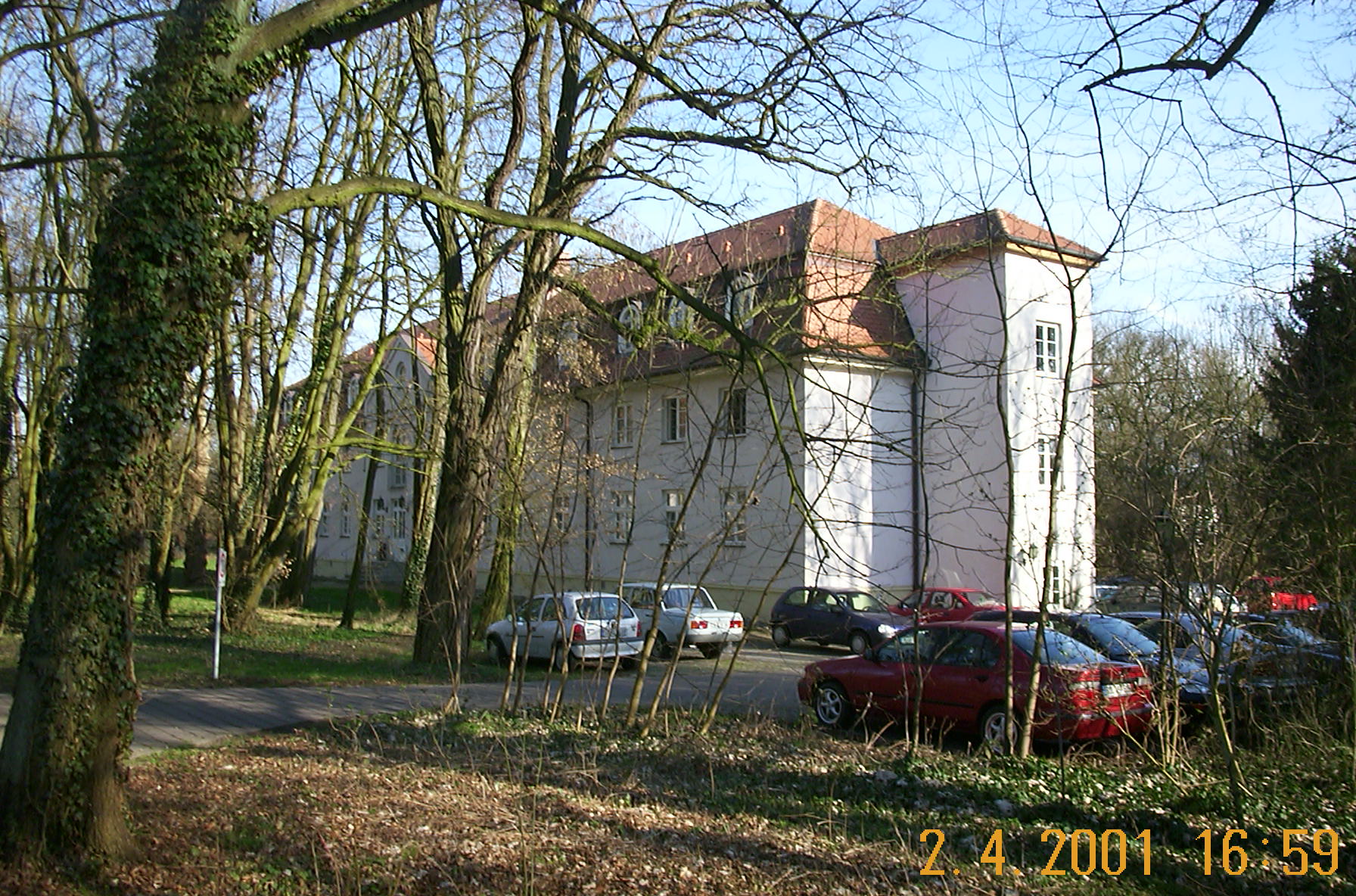 Historische Aufnahme des Kavaliershauses am Hotel Schloss Storkau von 2001 mit parkenden Autos zwischen kahlen Bäumen