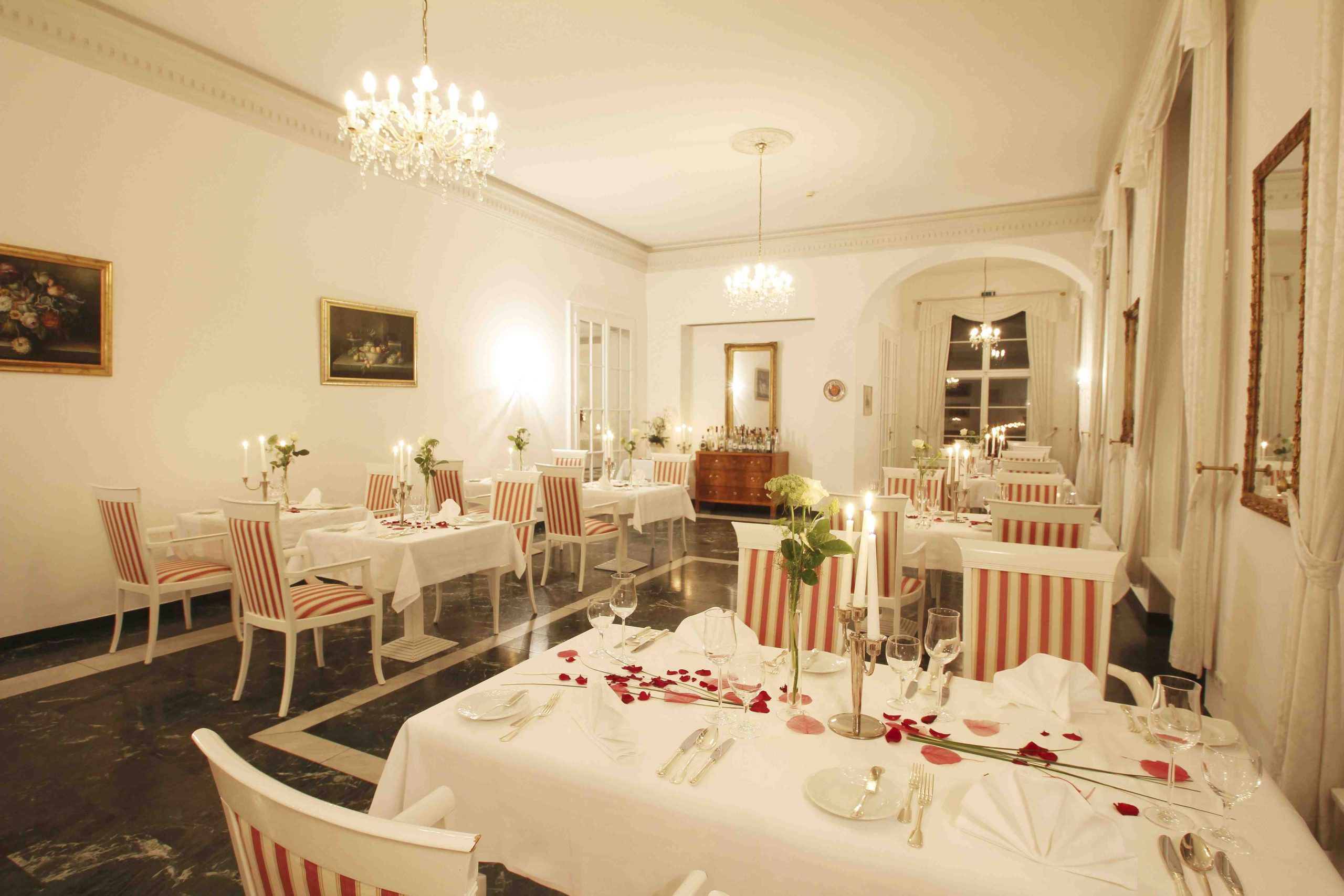 Festlich eingedecktes Restaurant im Hotel Schloss Storkau mit weißen Tischdecken, Kerzenleuchtern und Kristallkronleuchtern