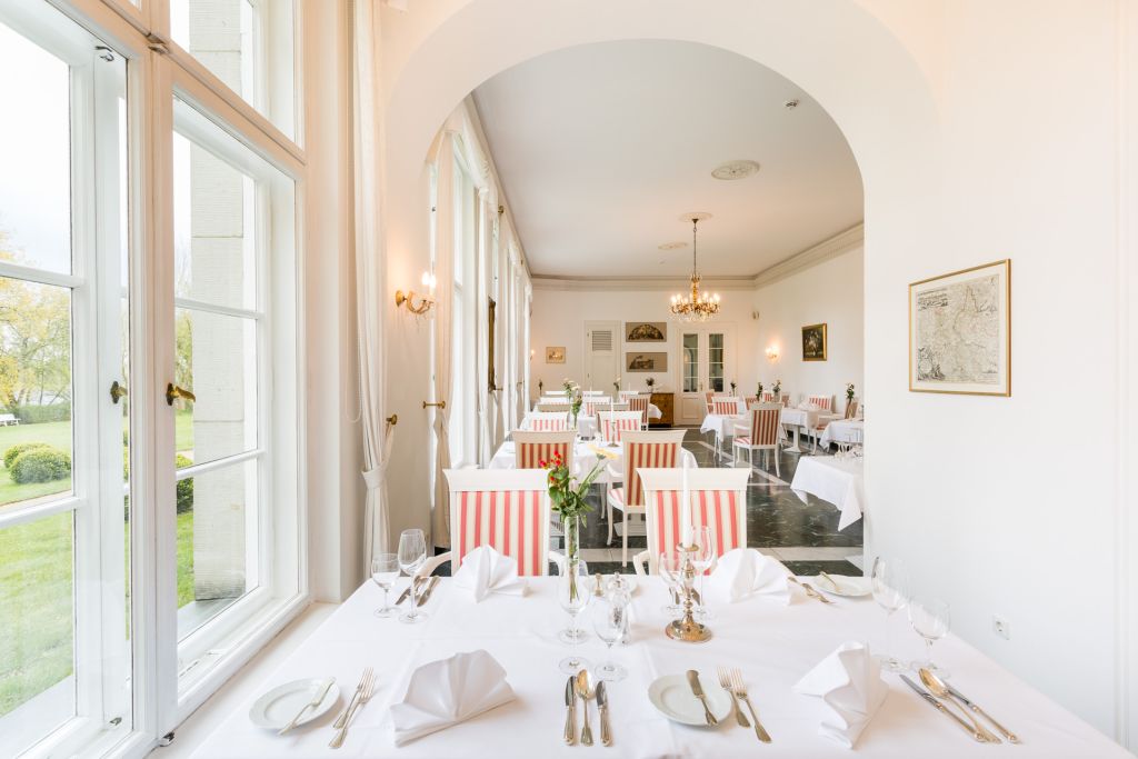 Fenstertisch mit Saalblick Gedeckter Tisch am Fenster mit Blick durch den Rundbogen in den Restaurantsaal des Hotel Schloss Storkau