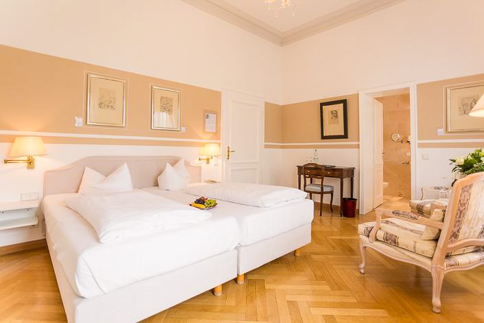Deluxe-Zimmer im Hotel Schloss Storkau mit Doppelbett, Schreibtisch und Blick in das marmorgeflieste Badezimmer
