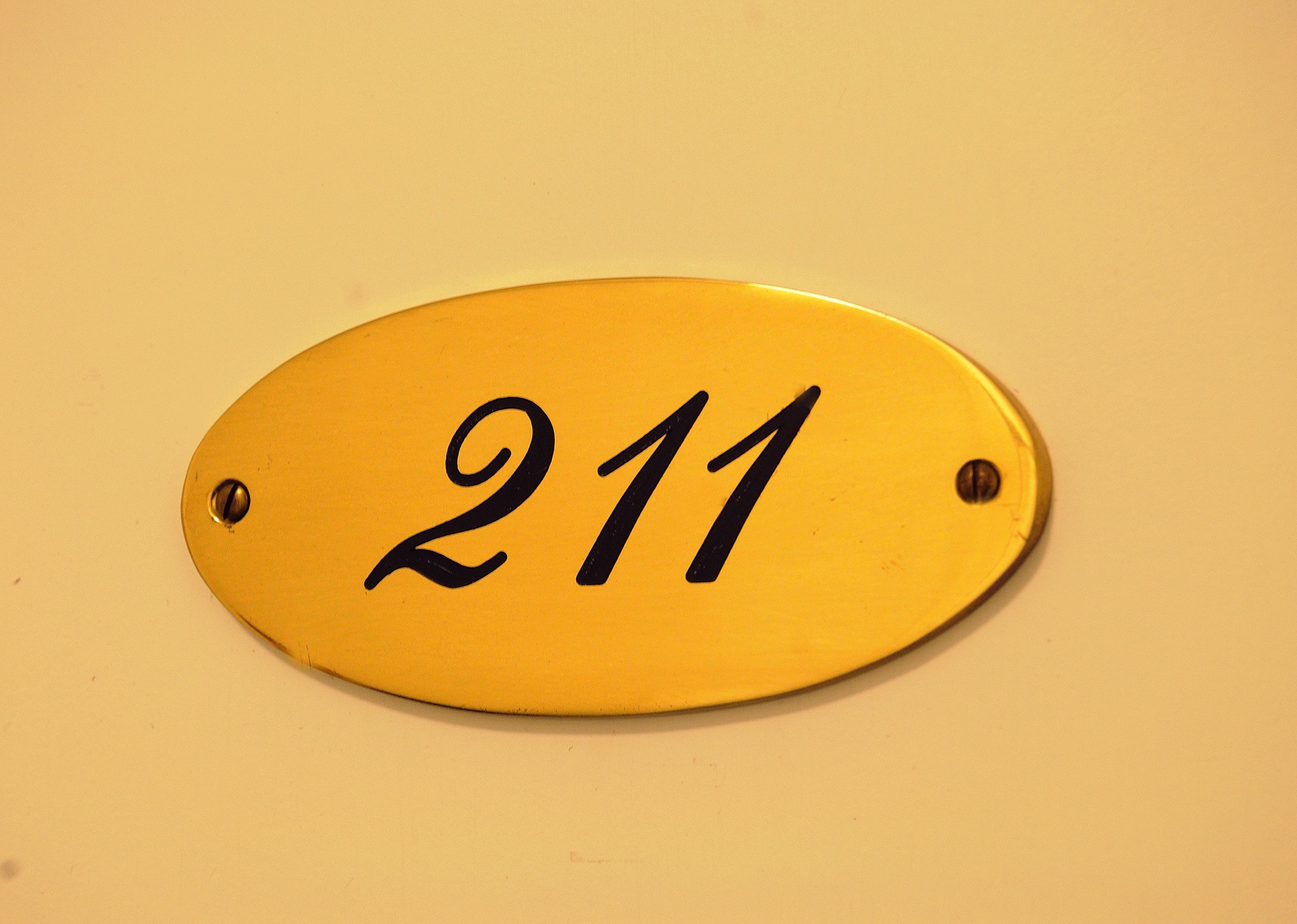 Zimmerdetail – Türschild 211 Ovales Messingschild mit der Zimmernummer 211 an einer Zimmertür im Hotel Schloss Storkau