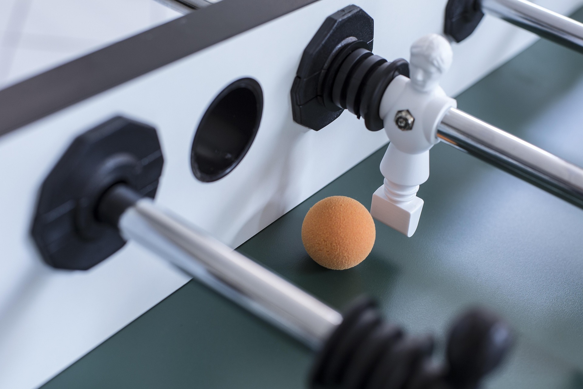 Tischkicker mit Ball Nahaufnahme eines Tischkickers mit weißer Spielfigur und orangefarbenem Ball